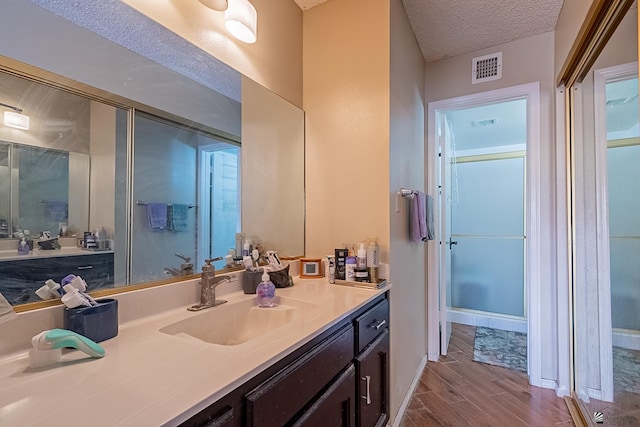 bathroom with vanity, wood finished floors, visible vents, and a textured ceiling