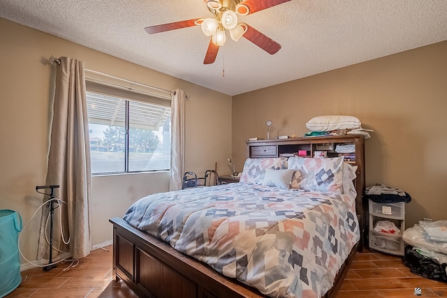 bedroom featuring a ceiling fan, a textured ceiling, and wood tiled floor