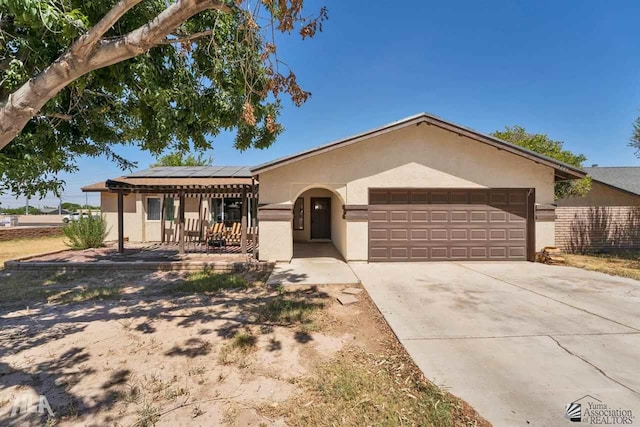 ranch-style home featuring solar panels, a porch, and a garage