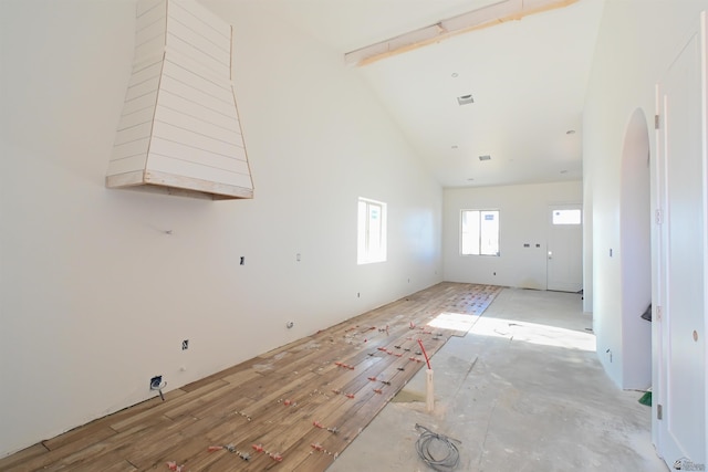 empty room featuring beamed ceiling and high vaulted ceiling