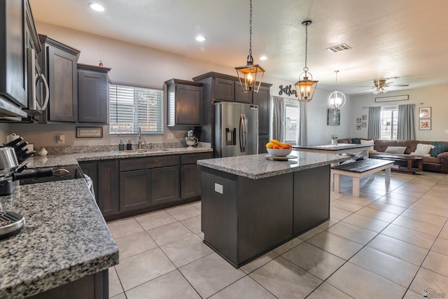 kitchen featuring sink, hanging light fixtures, dark brown cabinets, stainless steel appliances, and a kitchen island