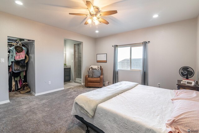 bedroom with ceiling fan, a spacious closet, light carpet, and ensuite bath