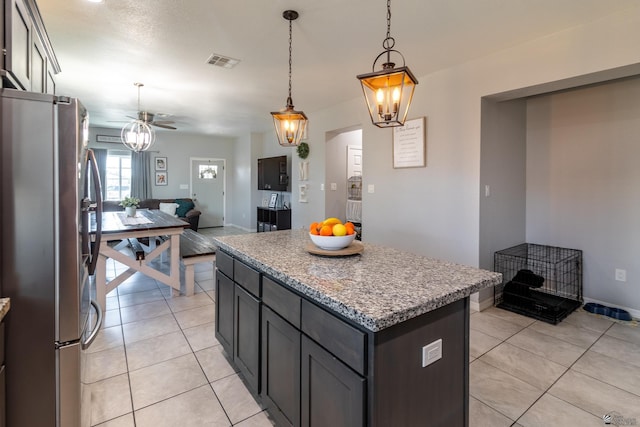 kitchen with a center island, hanging light fixtures, light tile patterned floors, stainless steel refrigerator, and ceiling fan