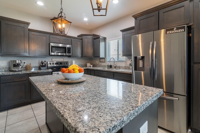 kitchen featuring a kitchen island, sink, hanging light fixtures, stainless steel appliances, and dark brown cabinets