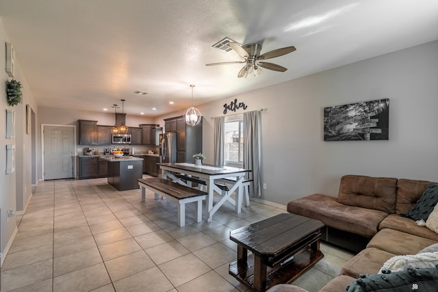 living room featuring ceiling fan with notable chandelier and light tile patterned floors