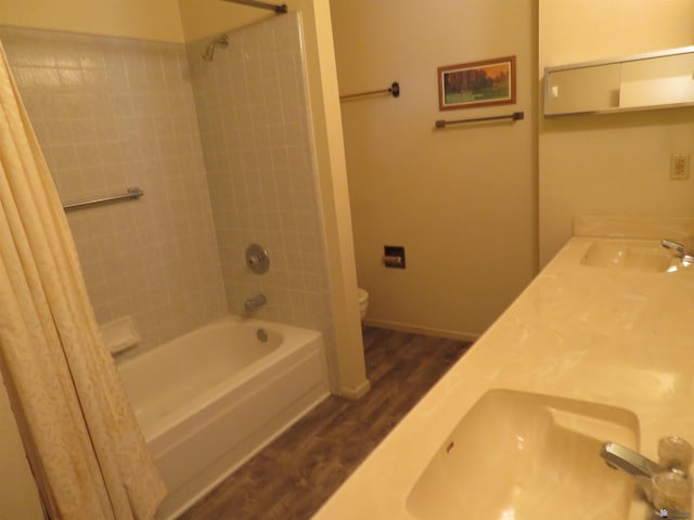 bathroom featuring a sink, shower / bathtub combination with curtain, toilet, and wood finished floors