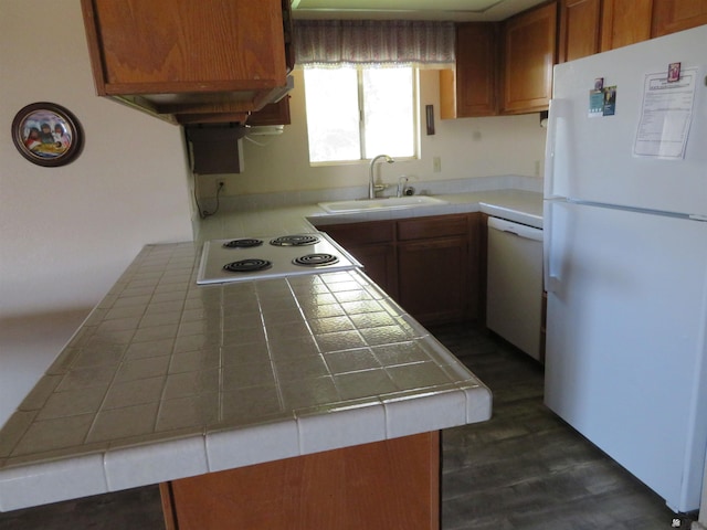 kitchen featuring brown cabinetry, tile countertops, white appliances, and a sink