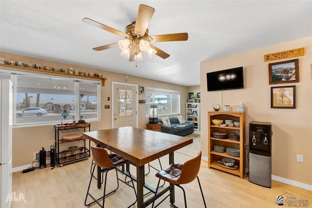 dining room with a textured ceiling, ceiling fan, and light hardwood / wood-style flooring