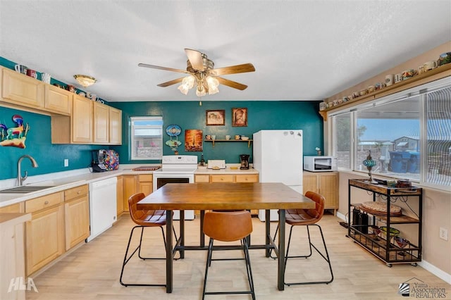 kitchen featuring sink, light brown cabinets, white appliances, and light wood-type flooring