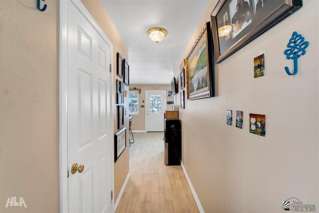 hallway with a textured ceiling and light wood-type flooring