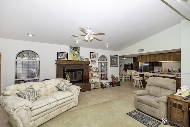 tiled living room with ceiling fan, lofted ceiling, and a brick fireplace