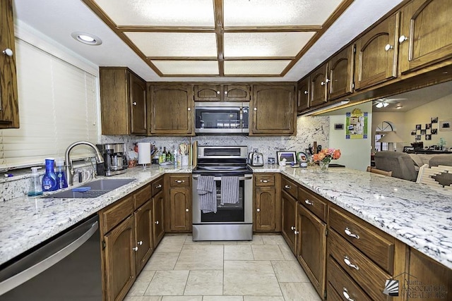 kitchen with sink, tasteful backsplash, light tile patterned flooring, light stone counters, and stainless steel appliances