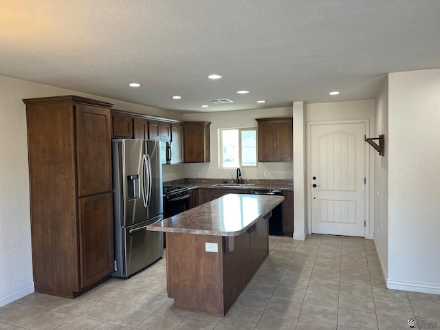 kitchen featuring a breakfast bar, a center island, sink, dark brown cabinets, and stainless steel appliances