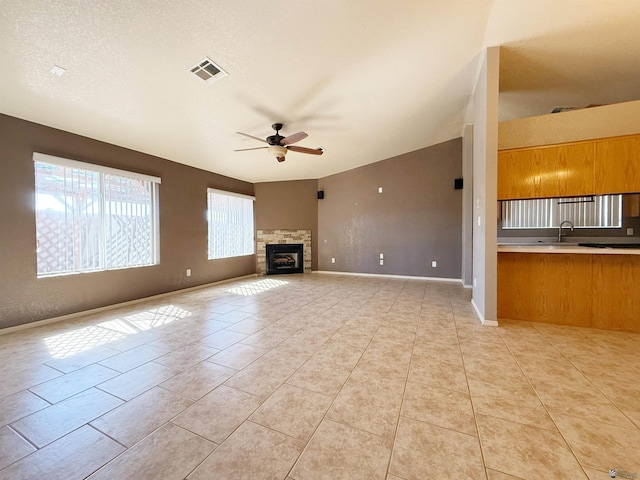 unfurnished living room featuring sink, light tile patterned floors, a textured ceiling, and ceiling fan