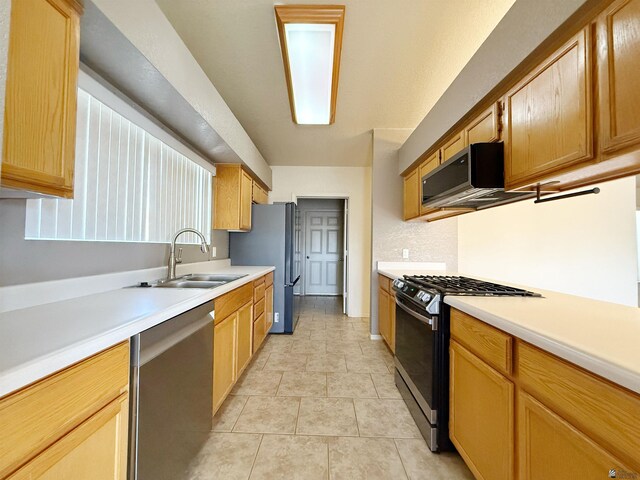 kitchen with appliances with stainless steel finishes, sink, and light tile patterned floors