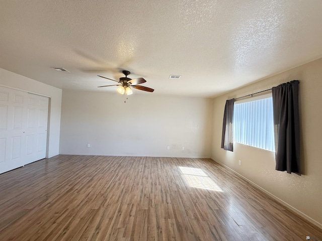 empty room featuring hardwood / wood-style floors, a textured ceiling, and ceiling fan