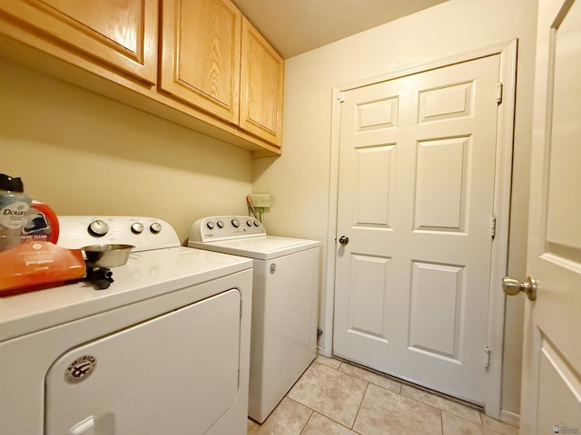 washroom with cabinets, light tile patterned floors, and washing machine and clothes dryer