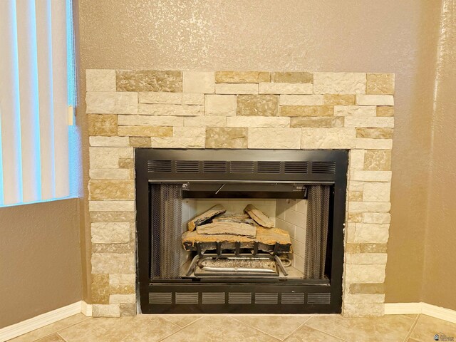 unfurnished room with vaulted ceiling, ceiling fan, light tile patterned floors, and a stone fireplace