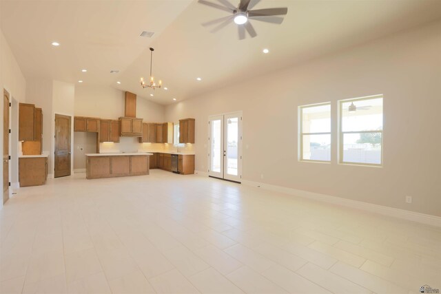 kitchen featuring french doors, high vaulted ceiling, hanging light fixtures, a kitchen island, and ceiling fan with notable chandelier