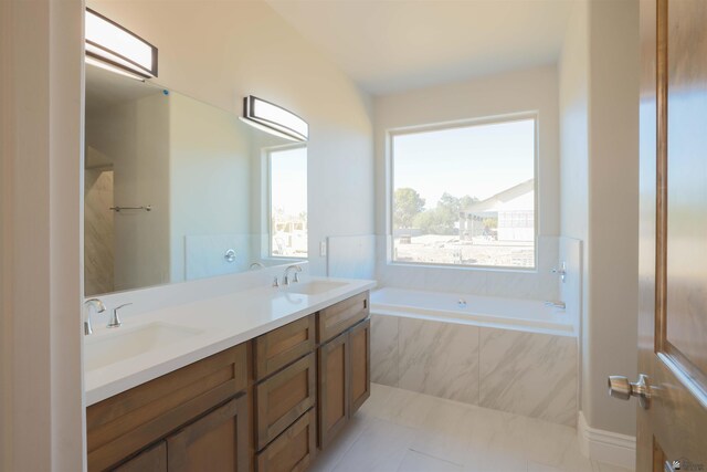 bathroom with vanity, tiled bath, and tile patterned flooring