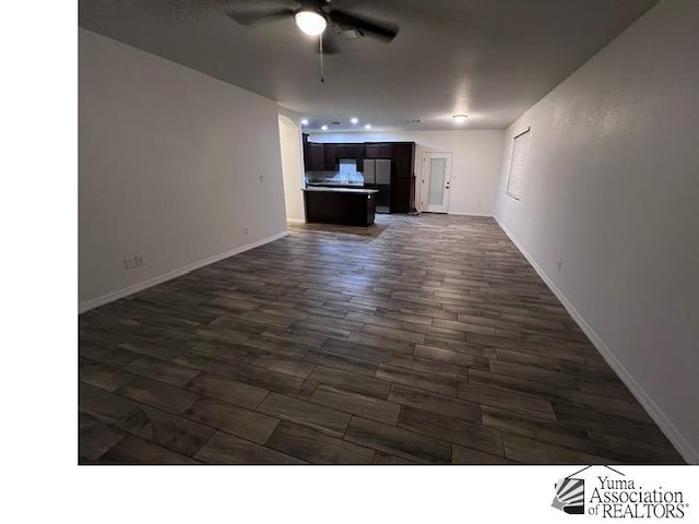 unfurnished living room with ceiling fan and dark wood-type flooring