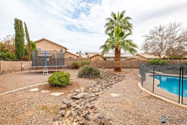 view of yard featuring a fenced in pool, a trampoline, and a fenced backyard