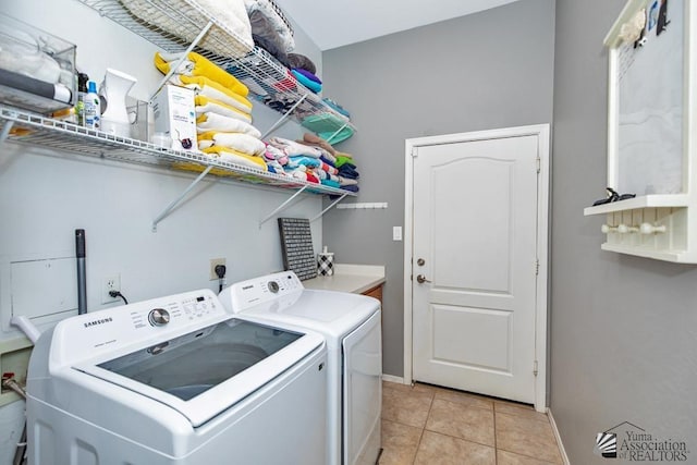 washroom featuring washing machine and clothes dryer, laundry area, baseboards, and light tile patterned floors