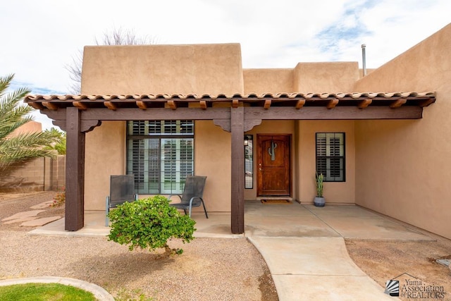 view of exterior entry featuring stucco siding and a tiled roof