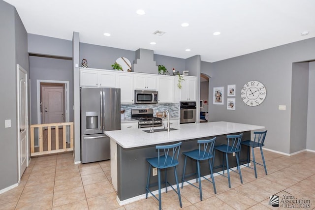 kitchen with a sink, backsplash, stainless steel appliances, arched walkways, and white cabinets