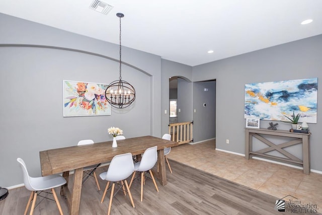 dining space with visible vents, arched walkways, baseboards, and light wood finished floors