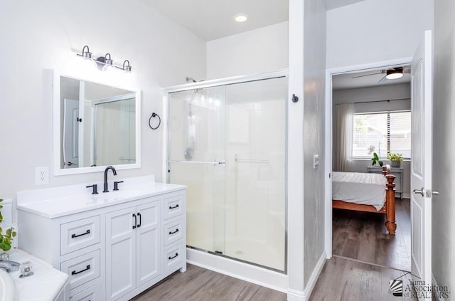 ensuite bathroom with vanity, a shower stall, wood finished floors, and a ceiling fan