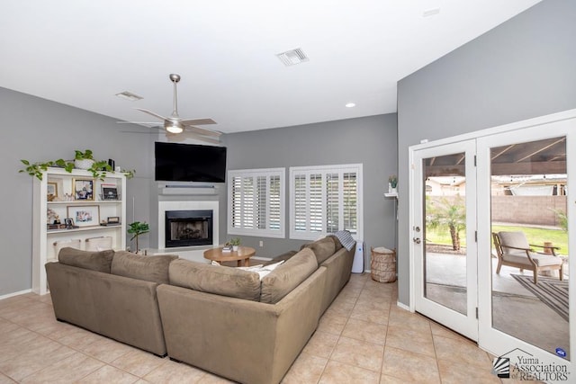 living area featuring a ceiling fan, light tile patterned flooring, a fireplace with raised hearth, and visible vents