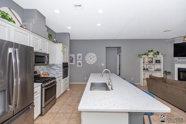 kitchen with tasteful backsplash, open floor plan, an island with sink, stainless steel appliances, and a sink