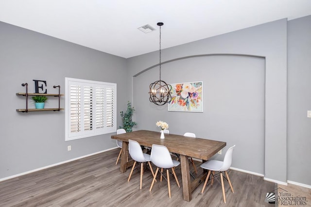 dining area with a chandelier, visible vents, baseboards, and wood finished floors