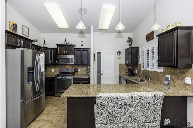 kitchen with dark brown cabinets, stainless steel appliances, decorative light fixtures, sink, and kitchen peninsula