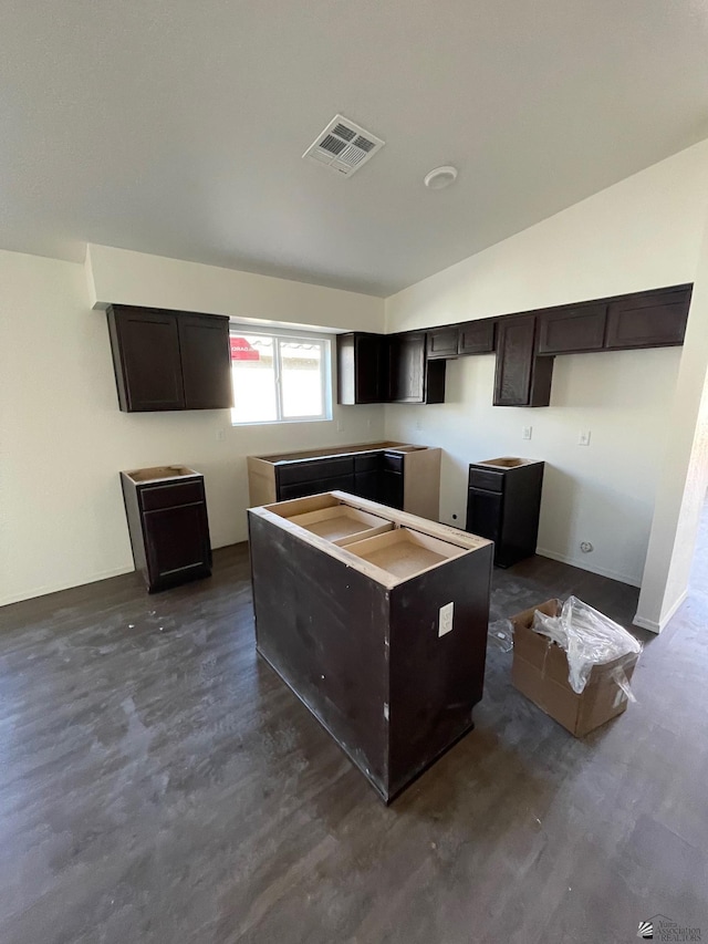 kitchen with dark brown cabinetry, a center island, dark hardwood / wood-style flooring, and vaulted ceiling