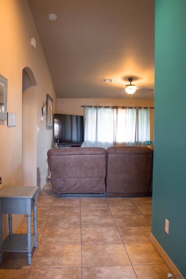 living area featuring visible vents, arched walkways, baseboards, and vaulted ceiling