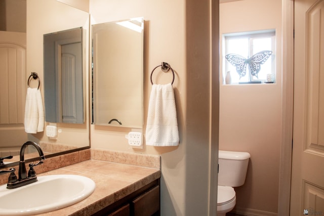 bathroom featuring vanity, toilet, and baseboards