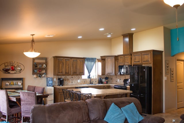 kitchen featuring black appliances, light countertops, pendant lighting, open floor plan, and backsplash