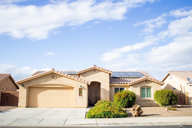 mediterranean / spanish home with stucco siding, roof mounted solar panels, concrete driveway, an attached garage, and a tiled roof