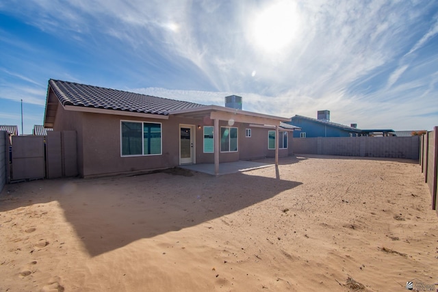 back of house featuring a tile roof, a patio area, a fenced backyard, and stucco siding