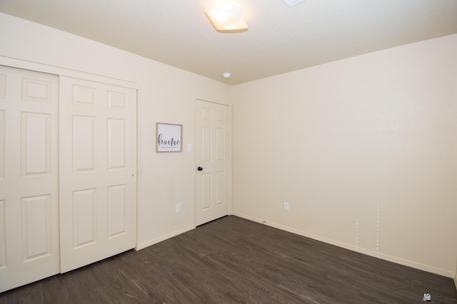 unfurnished bedroom with dark wood-style floors, baseboards, and a closet