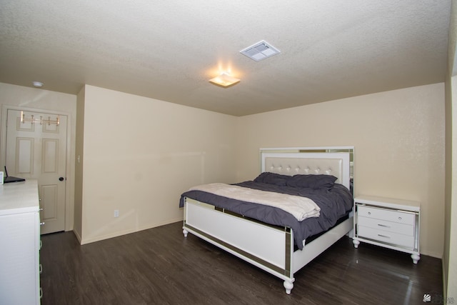 bedroom with baseboards, a textured ceiling, visible vents, and wood finished floors