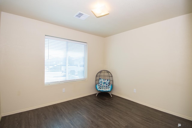 spare room with dark wood-type flooring, visible vents, and baseboards