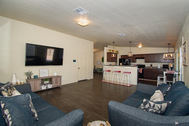 living room with vaulted ceiling, dark wood-type flooring, a textured ceiling, and visible vents