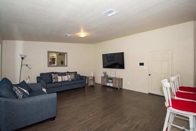 living area featuring dark wood-type flooring, visible vents, and a textured ceiling