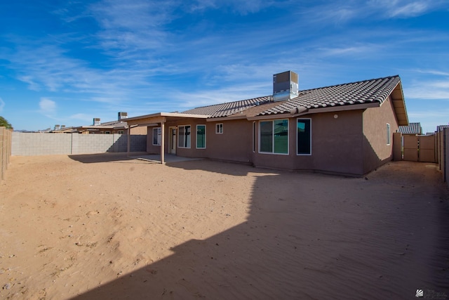 rear view of property featuring a tile roof, a fenced backyard, and stucco siding