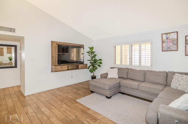 living area featuring light wood finished floors, visible vents, and high vaulted ceiling