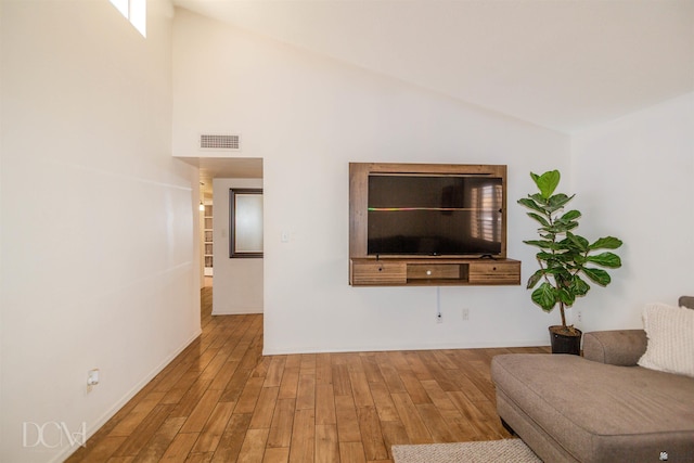 unfurnished living room with lofted ceiling, visible vents, and wood finished floors