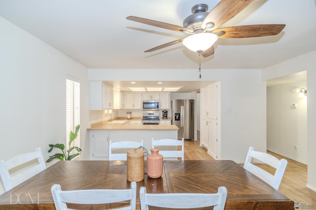 dining space featuring light wood-type flooring, ceiling fan, and baseboards